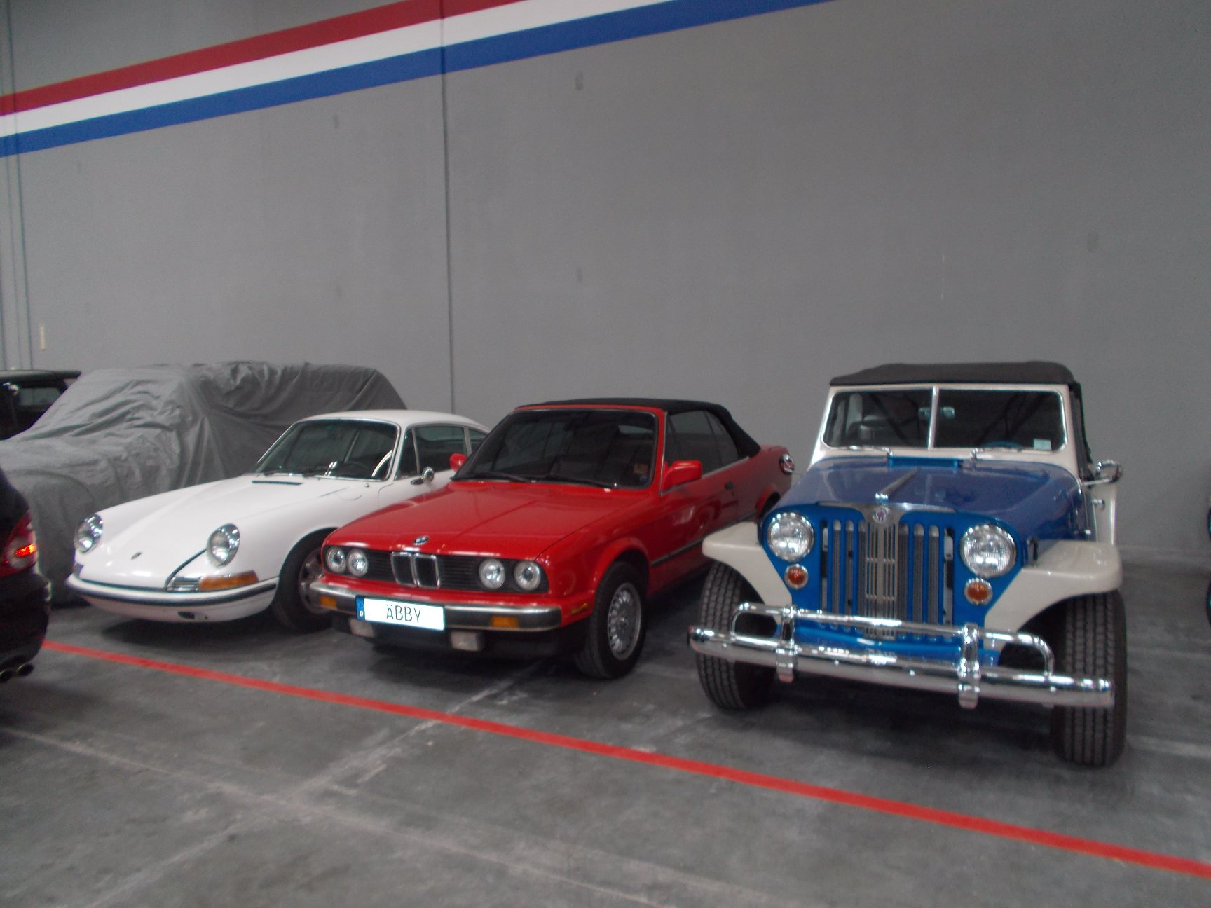 Porsche, BMW convertible, and vintage Jeepster at Auto Vault