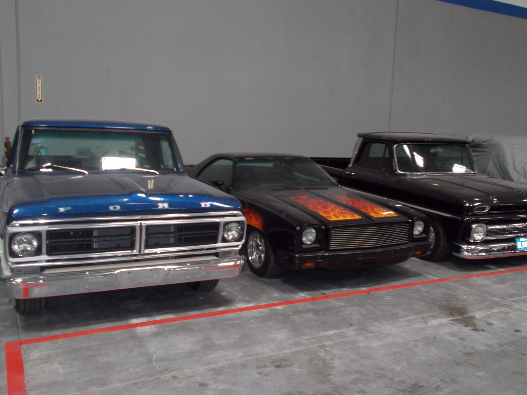 Vintage Ford pickup and flame-painted muscle cars in storage